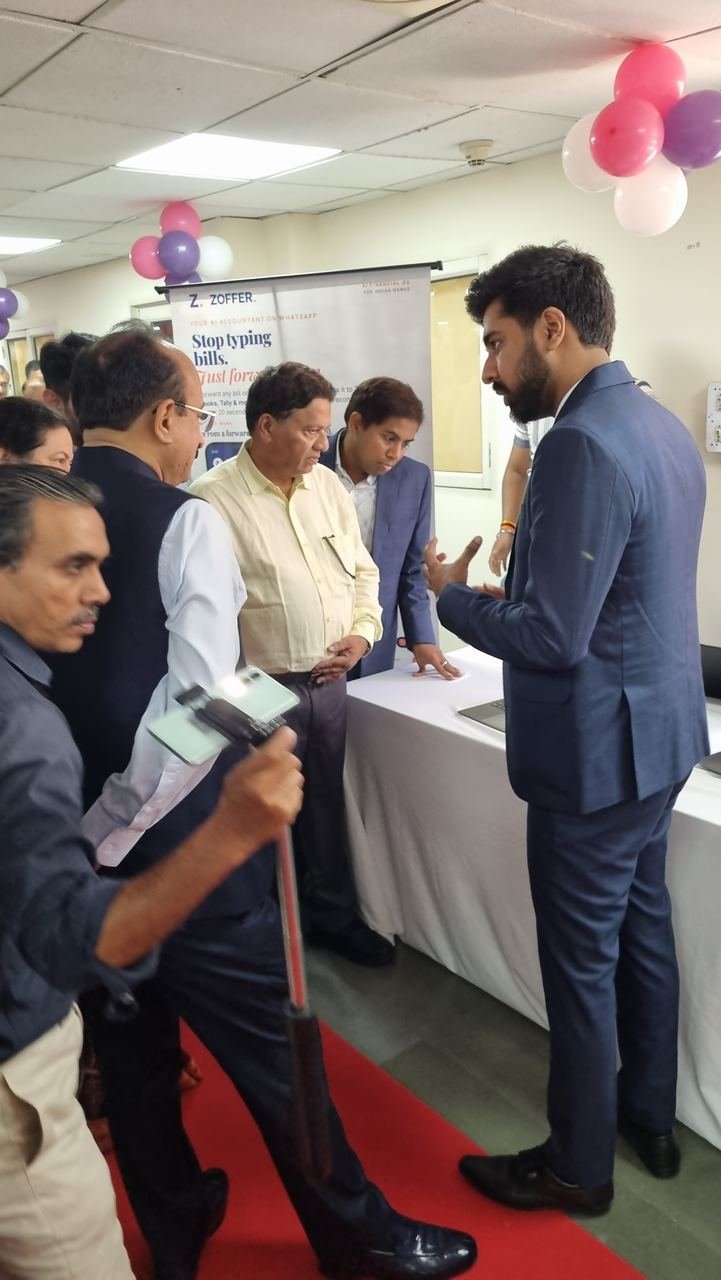 A Zoffer team member in a navy suit explaining the product to guests at the kiosk, with the Stop typing bills. Just forward them. standee behind the table
