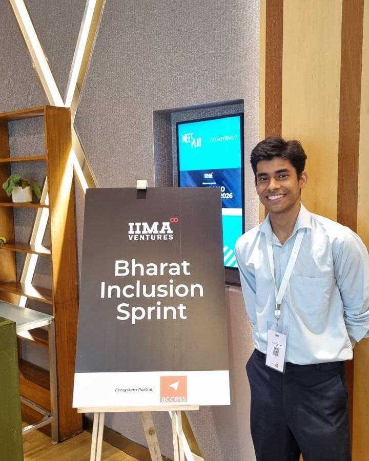 A Zoffer team member in a light blue shirt and event lanyard, smiling next to the IIMA Ventures Bharat Inclusion Sprint sign