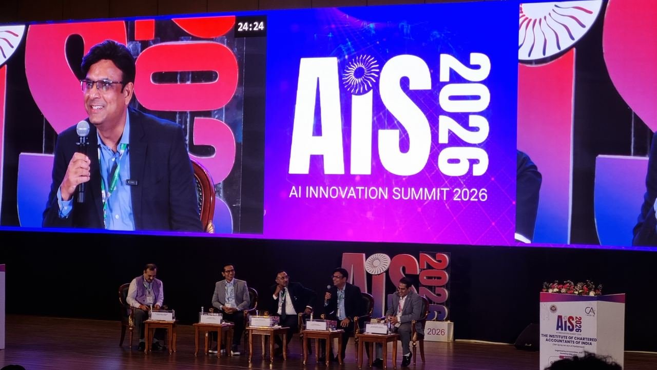 A five-person panel discussion on the AIS 2026 stage, with a speaker shown on the large screen beside the AI Innovation Summit 2026 logo