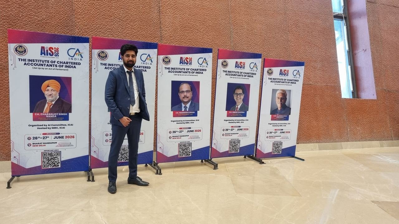 A Zoffer team member in a navy suit standing among a row of AIS 2026 standees from the Institute of Chartered Accountants of India at Bharat Mandapam