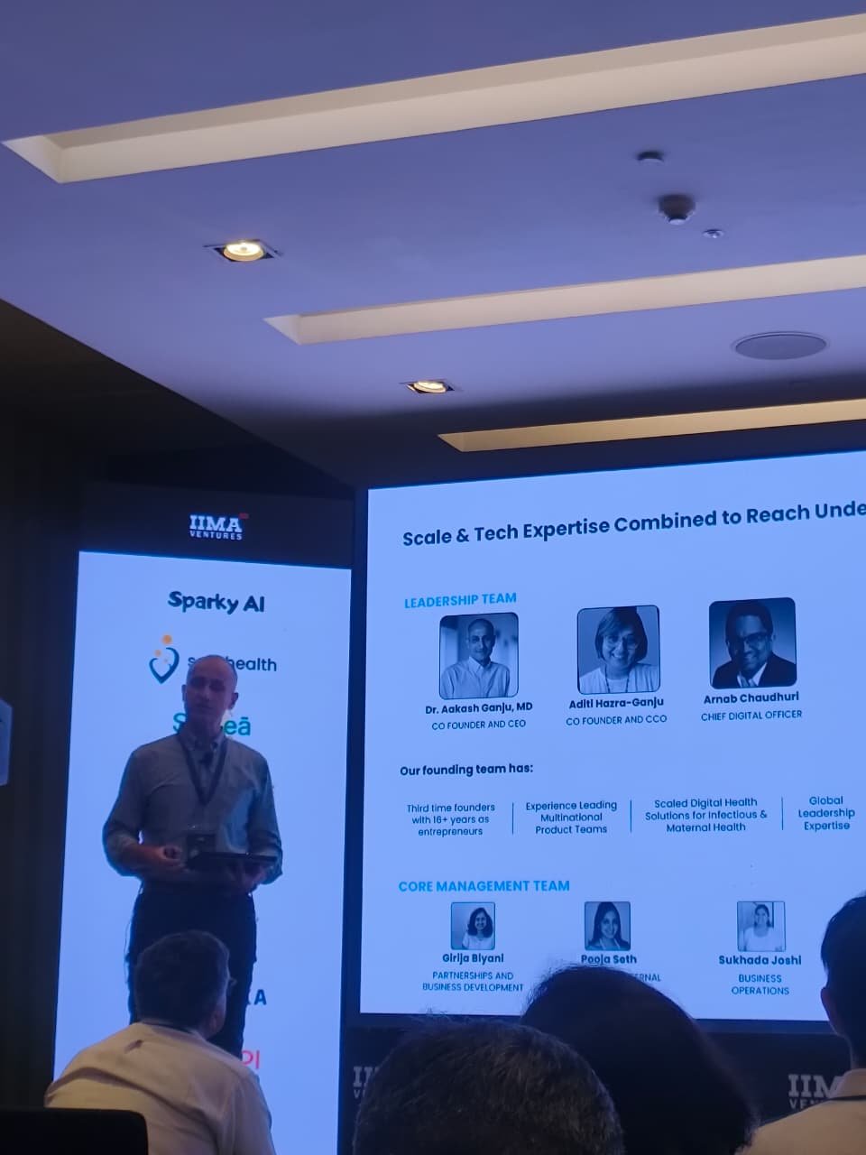 A founder presenting their leadership team on stage at the IIMA Ventures Bharat Inclusion Sprint, with the list of participating startups on the side screen