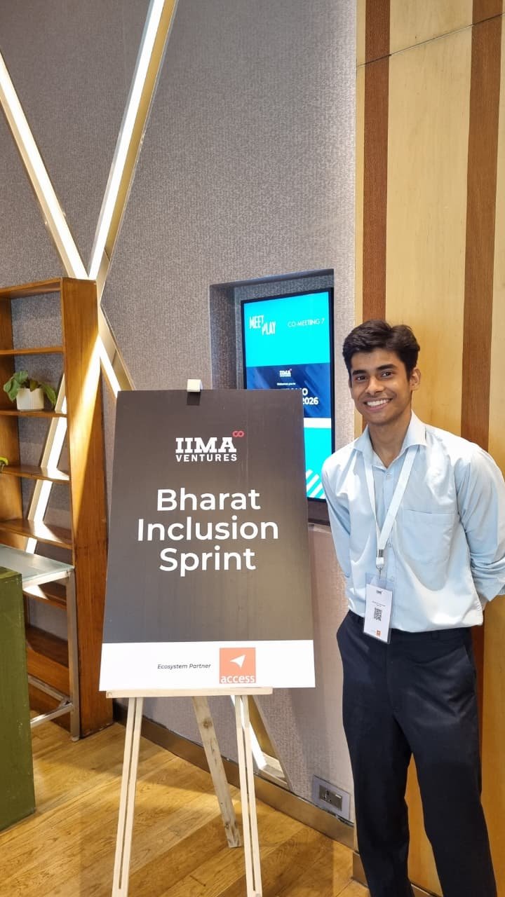 A Zoffer team member in a light blue shirt and event lanyard, smiling next to the IIMA Ventures Bharat Inclusion Sprint sign